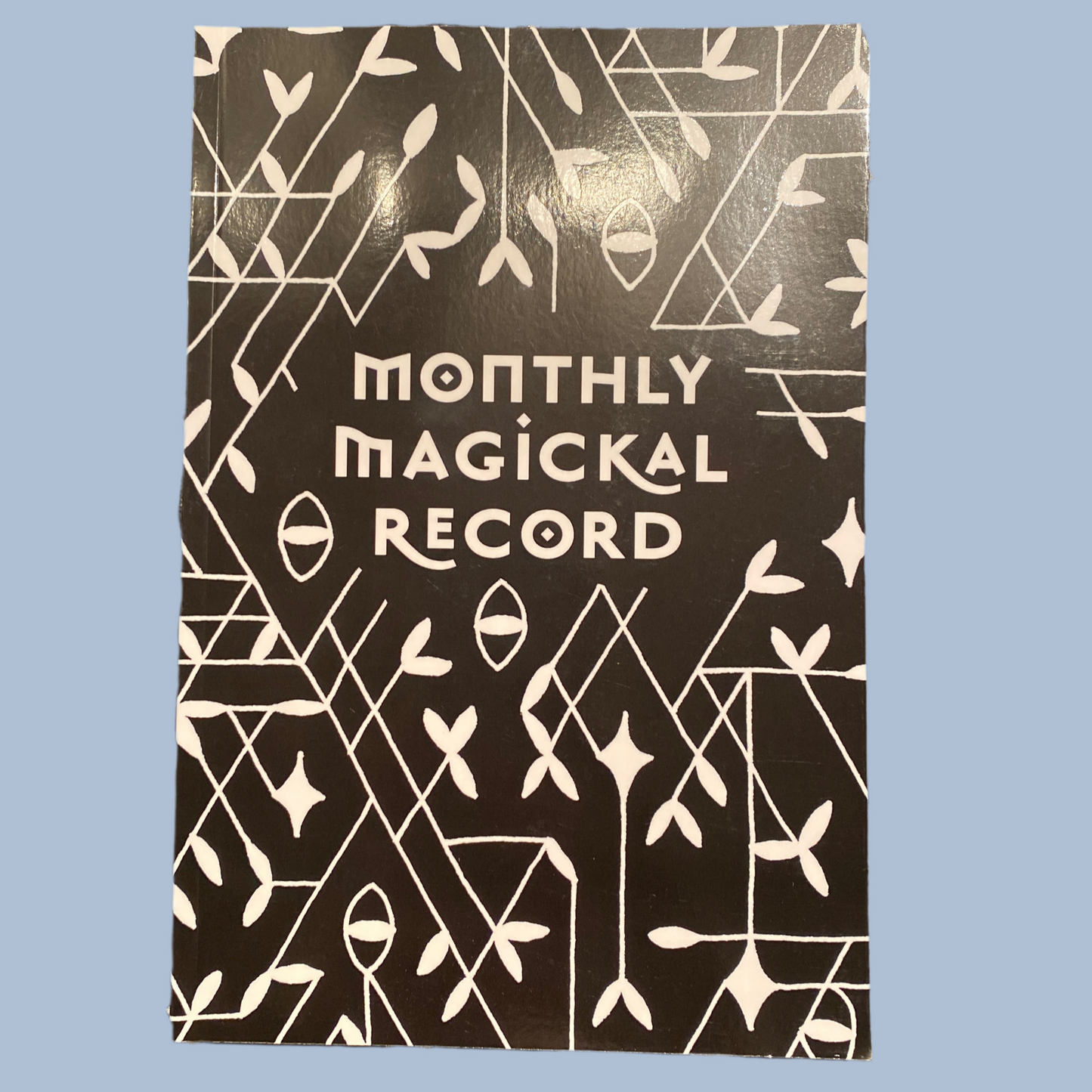 Monthly Magickal Record journal with black cover and white mystical abstract design