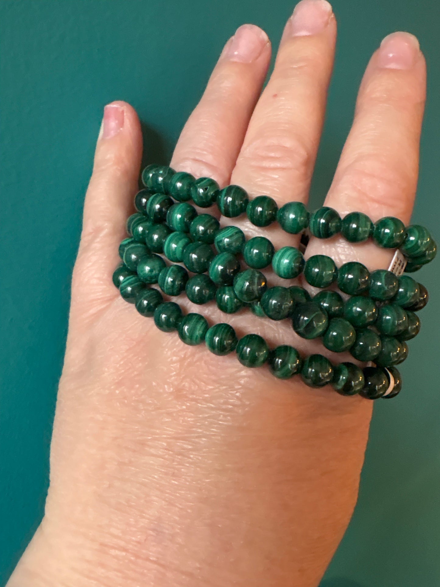 Bracelet Malachite 8mm vibrant green beads for protection and emotional healing wrapped around a hand