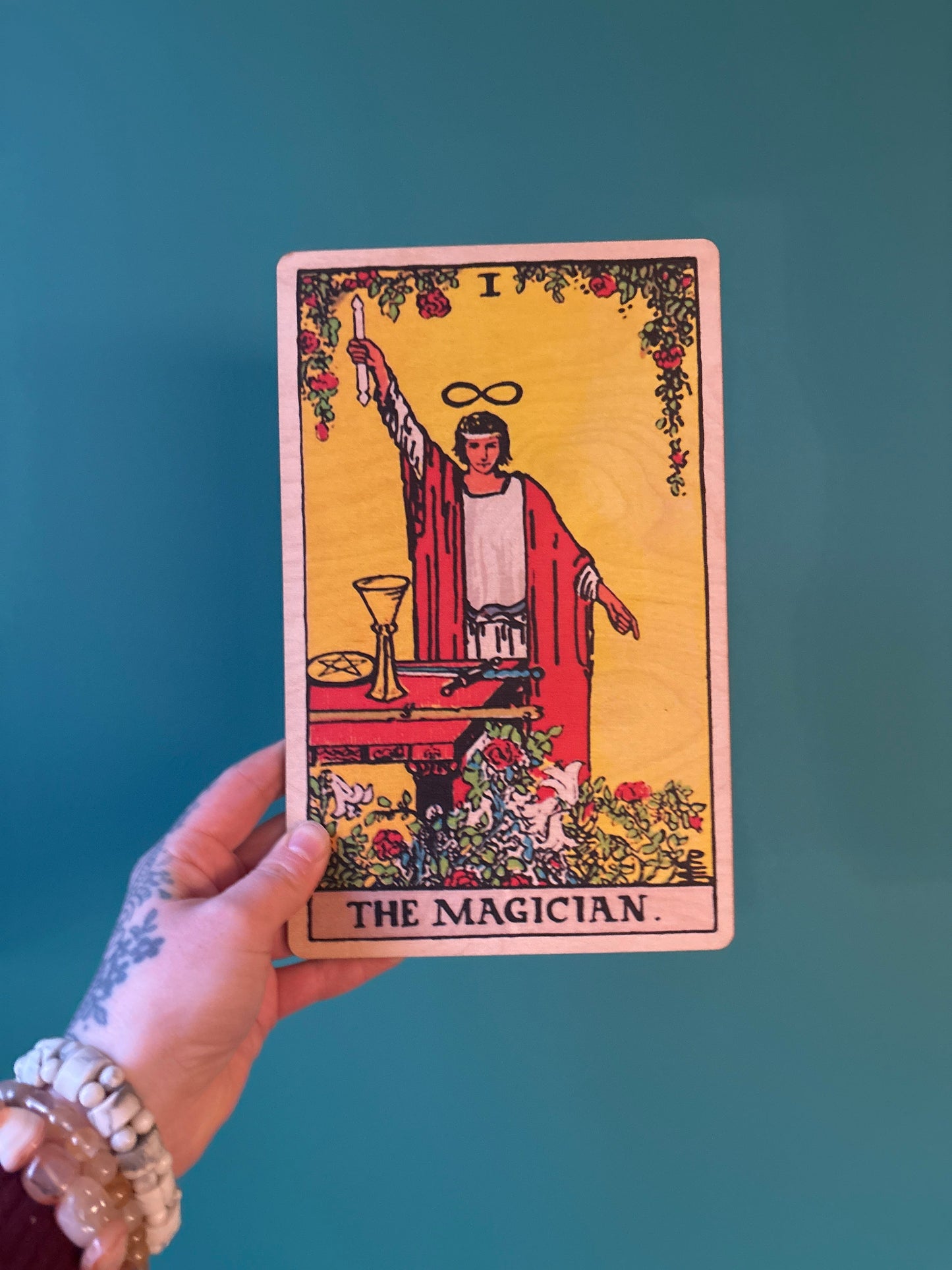 Wood wall art of Tarot card The Magician with detailed natural wood design held against blue background