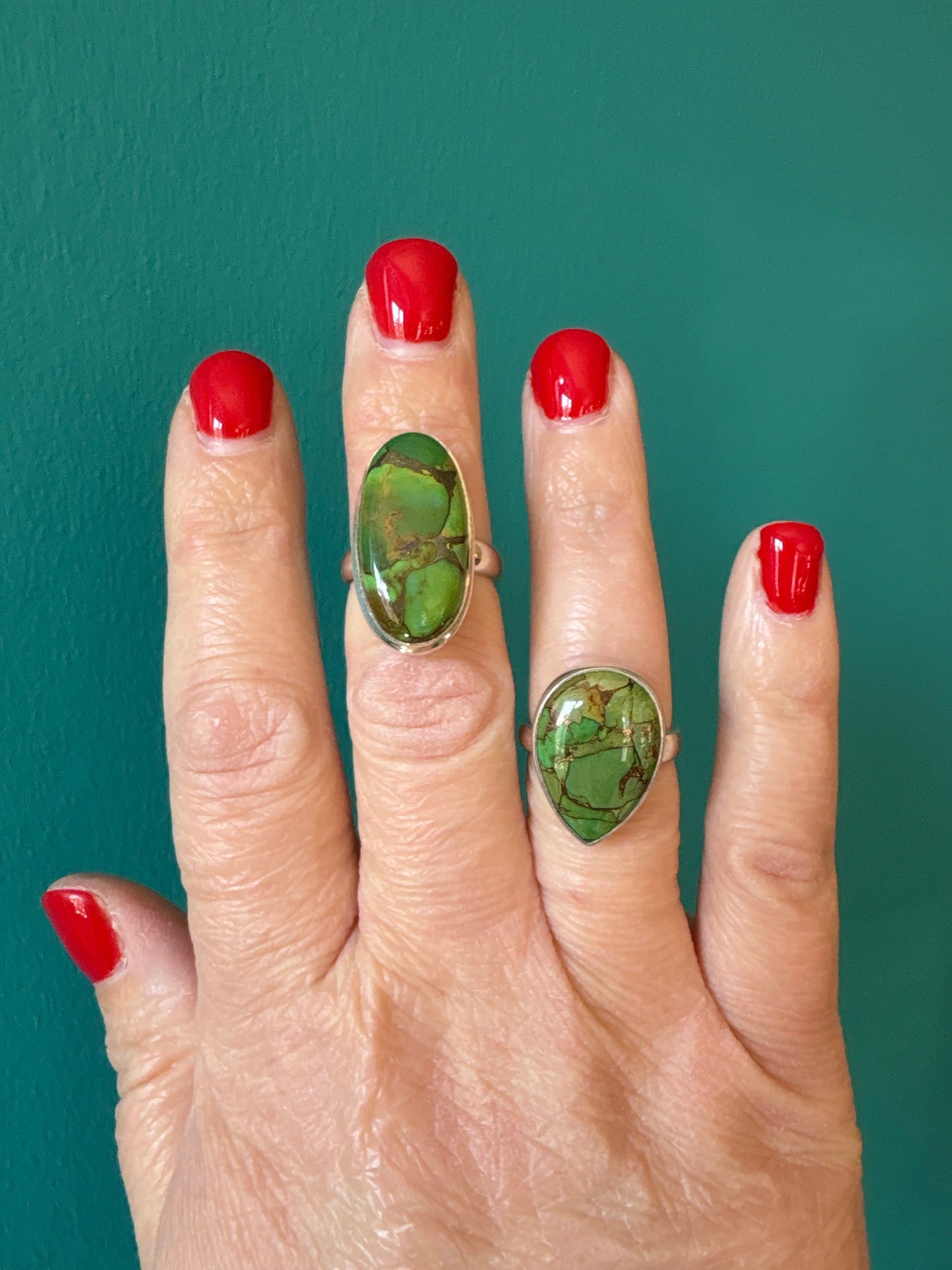 adjustable ring with green copper turquoise stone on hand with red nail polish
