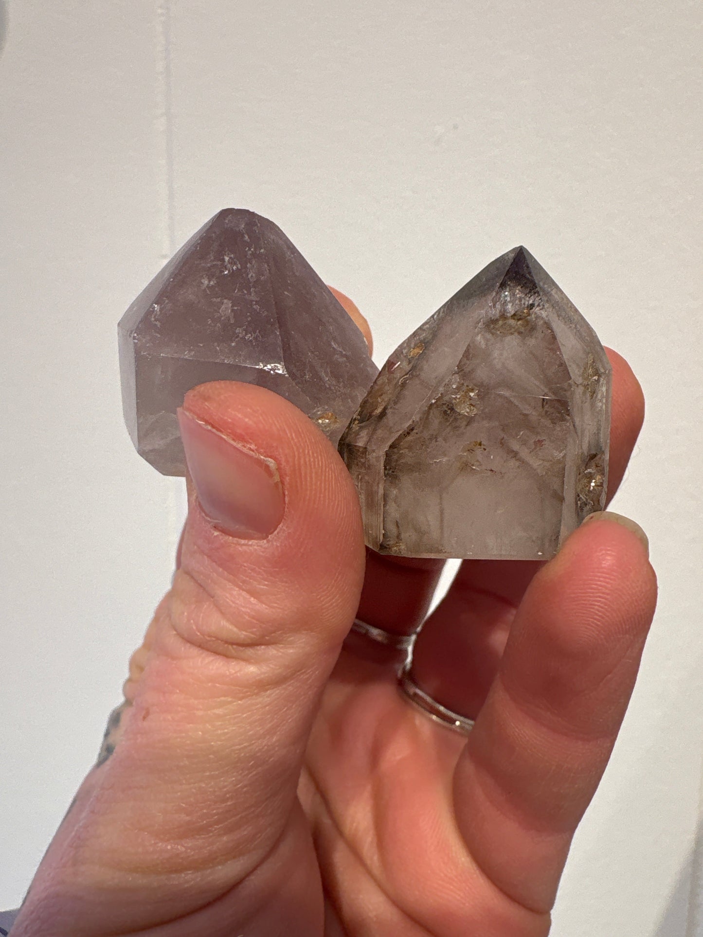 Hand holding two natural Amethyst Points with calming purple hues and clear crystal formations