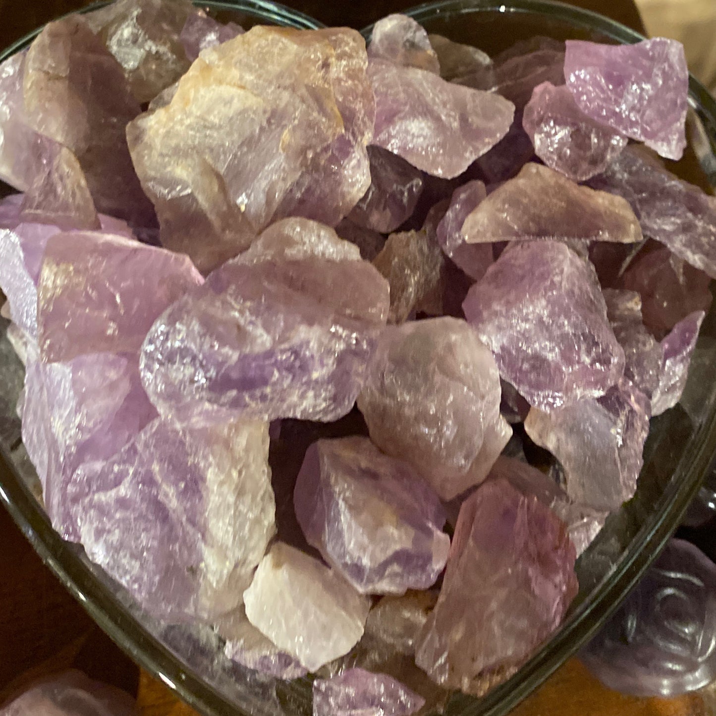 Raw amethyst chunks with natural purple hues in a heart-shaped container