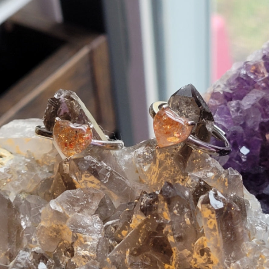Ring SunStone heart with orange gemstone on silver band displayed on crystal cluster