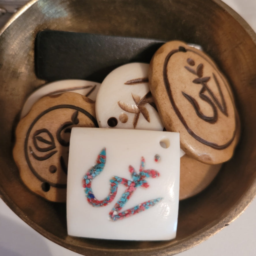 Mystery Tibetan Bone Pendant with spiritual symbols in a brass bowl