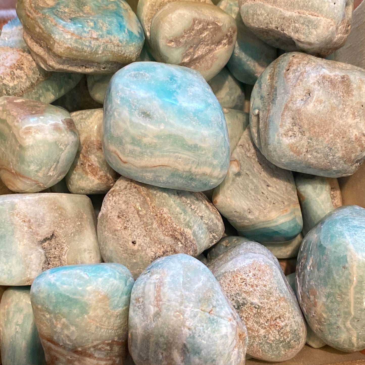 Close-up of smooth tumble blue aragonite stones with calming blue and beige tones