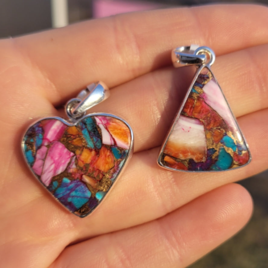 Close-up of heart and triangle shaped oyster turquoise pendants with colorful natural stone patterns held in hand