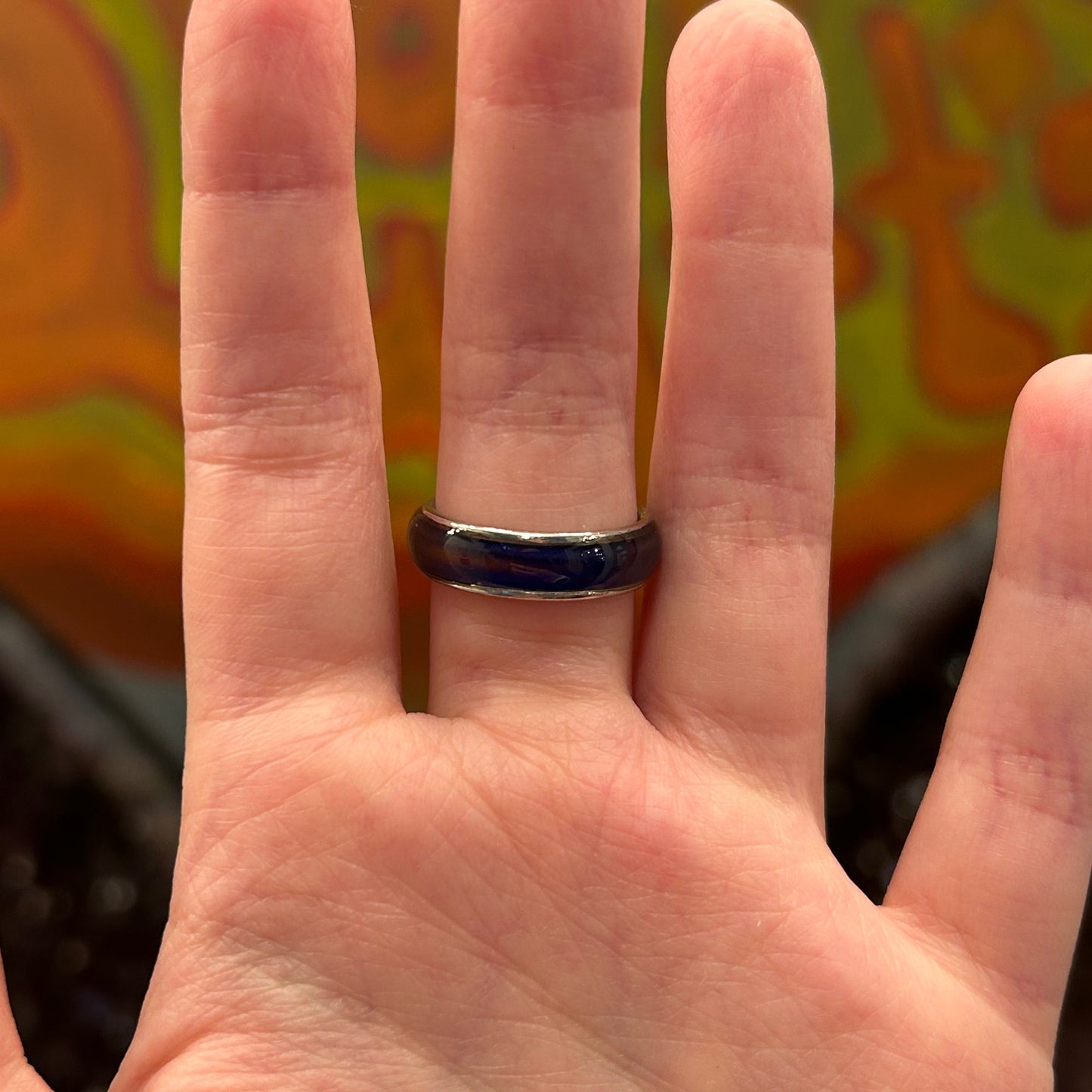 hand wearing a sleek black mood ring that changes color based on emotions