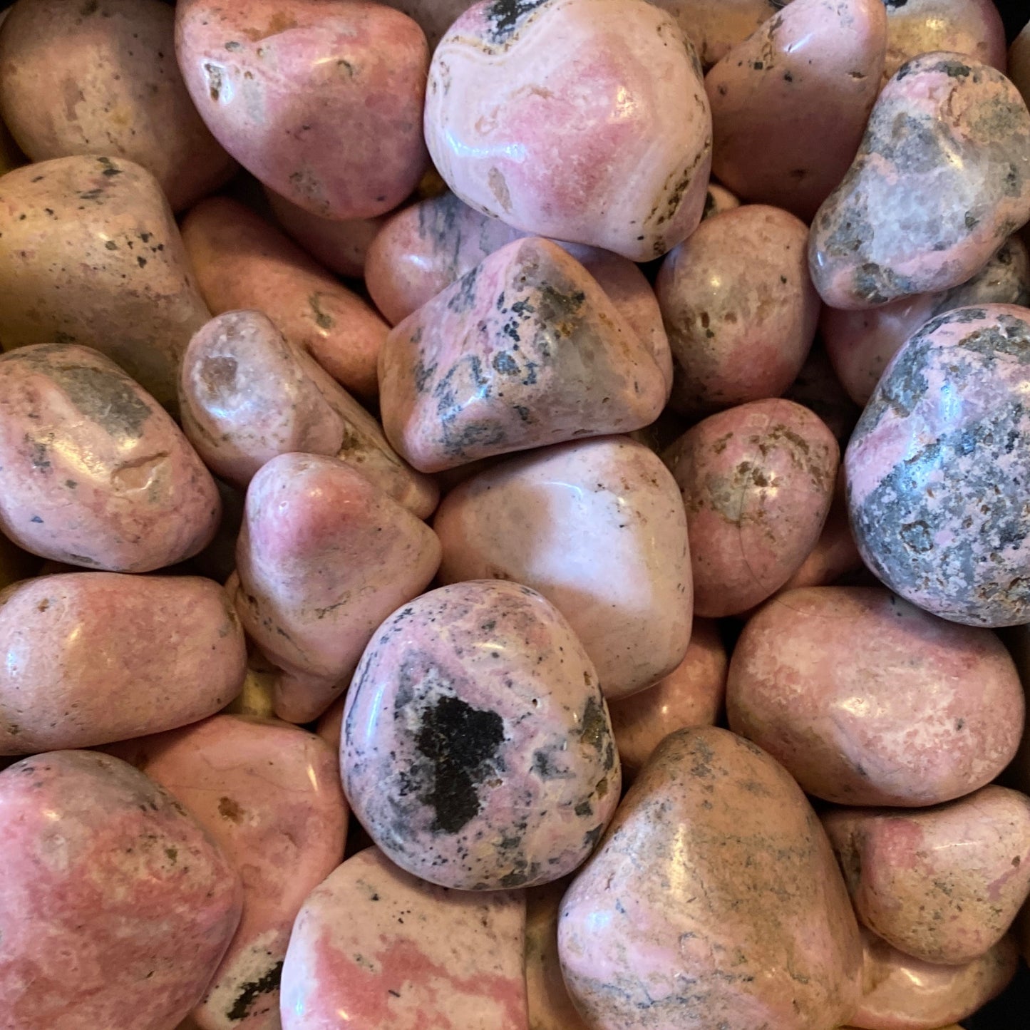 collection of polished Rhodonite tumble stones with pink and black patterns
