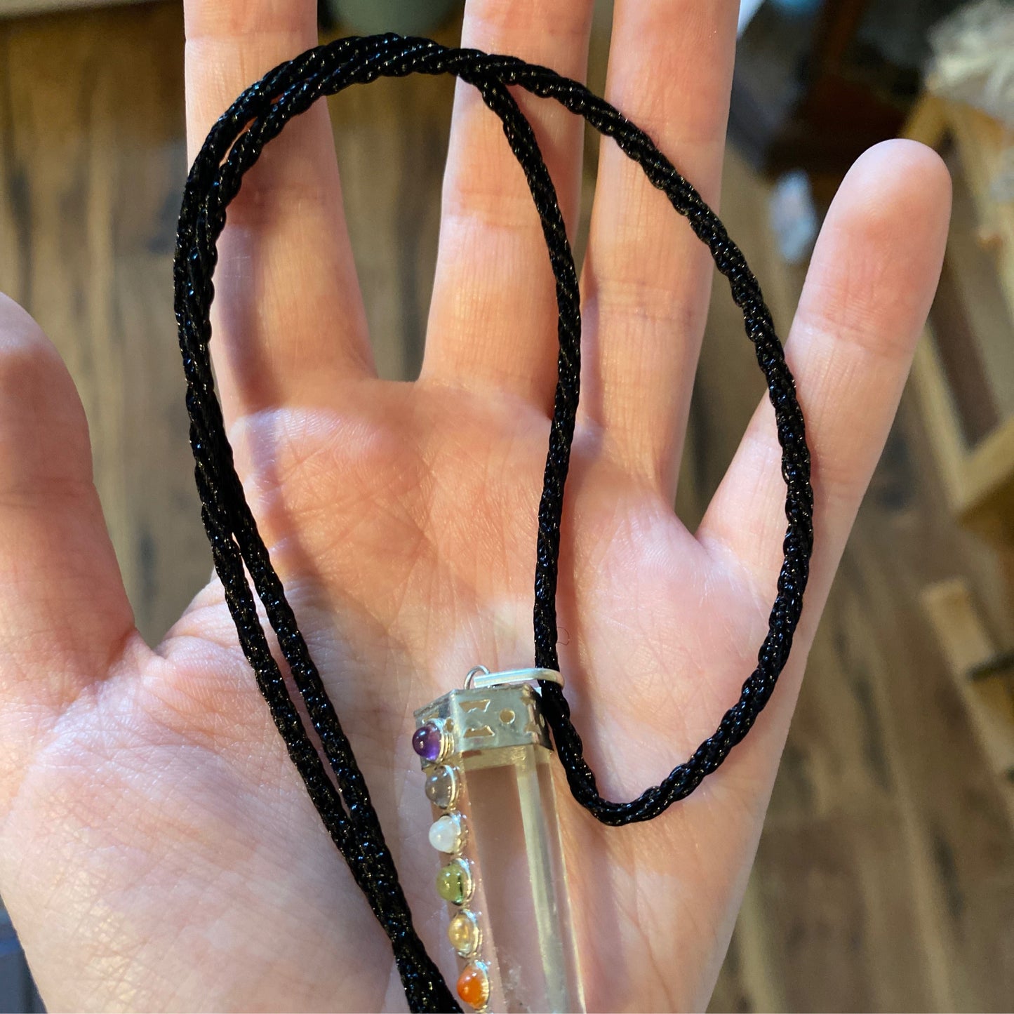 Black rope chain necklace with a crystal pendant held in a hand