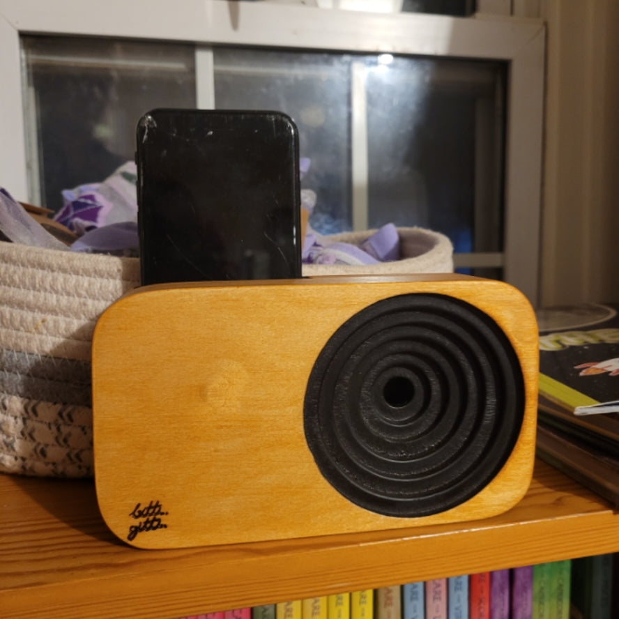 Wooden speaker sound system with a smartphone docked on top on a wooden shelf