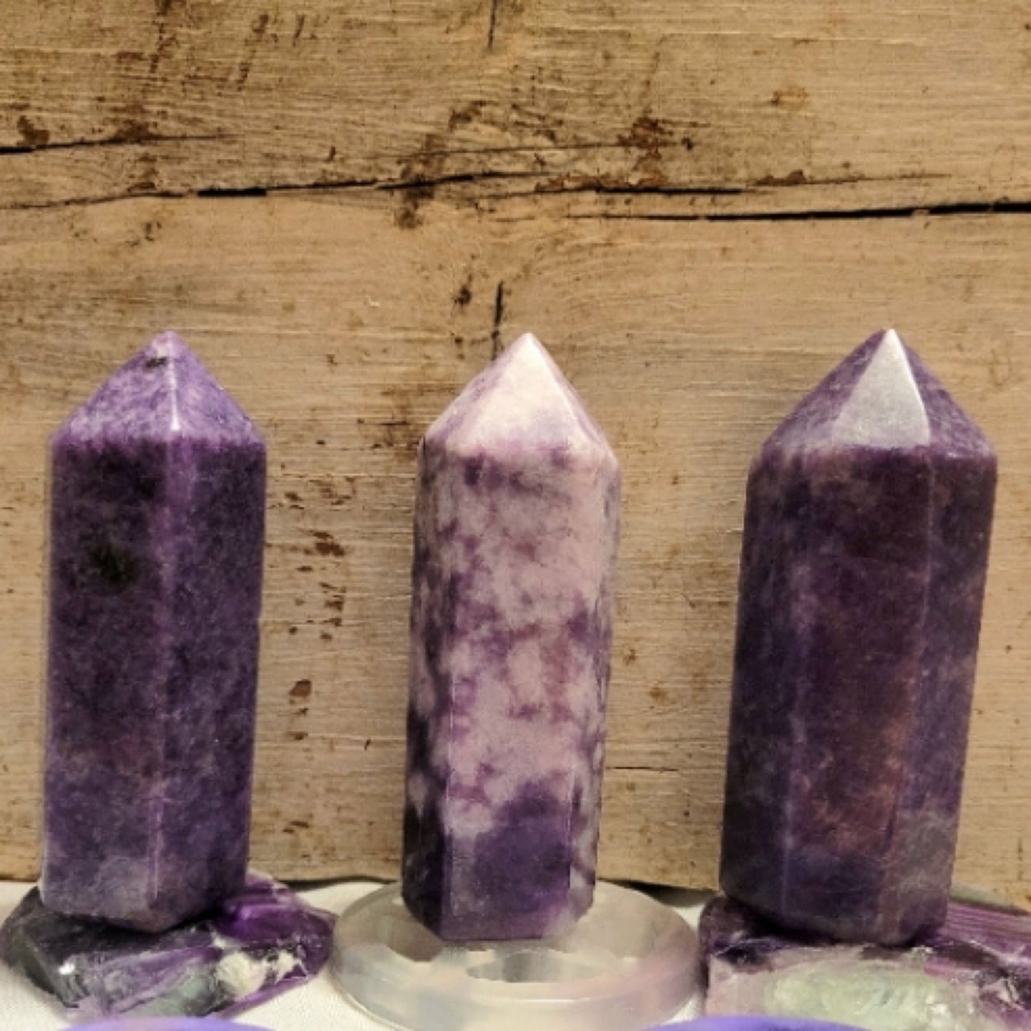 Small lepidolite tower crystals with purple and white hues on wooden surface