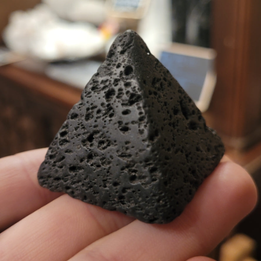 Black lava stone pyramid for essential oil diffusion held in hand