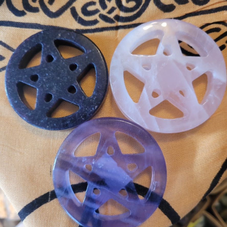 Set of three crystal pentacles in black, white, and purple with intricate geometric designs on patterned fabric background