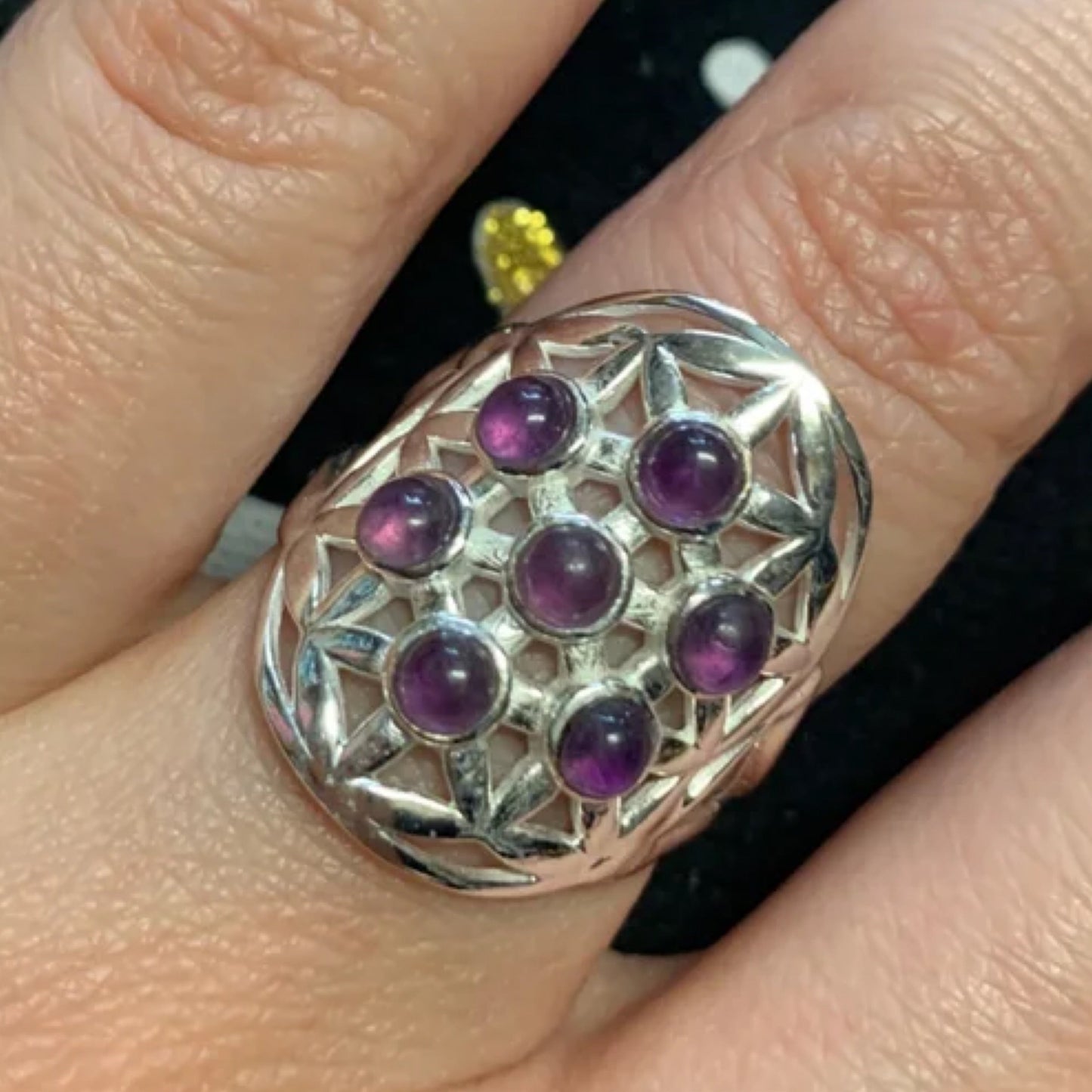 Adjustable sterling silver ring with amethyst stones forming a Flower of Life design on finger