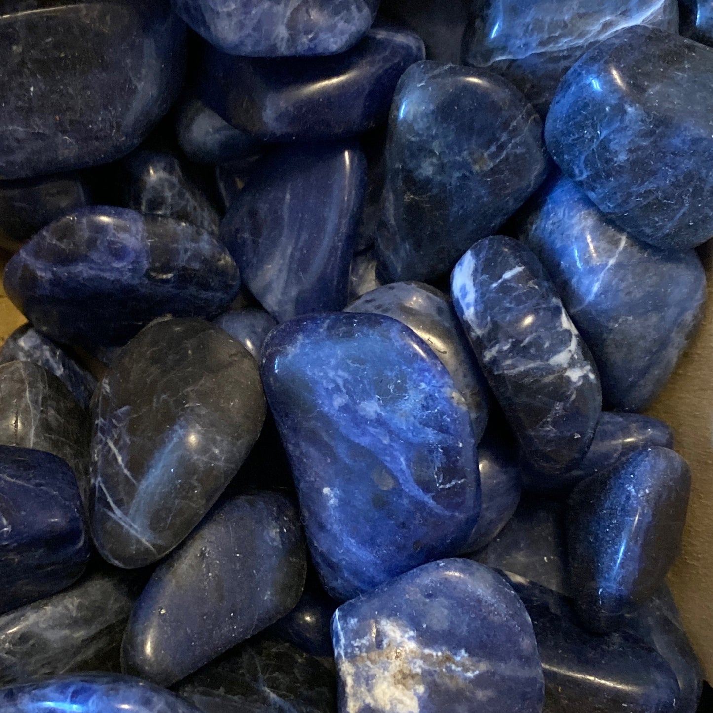 Polished deep blue sodalite tumble stones with white streaks and smooth surfaces