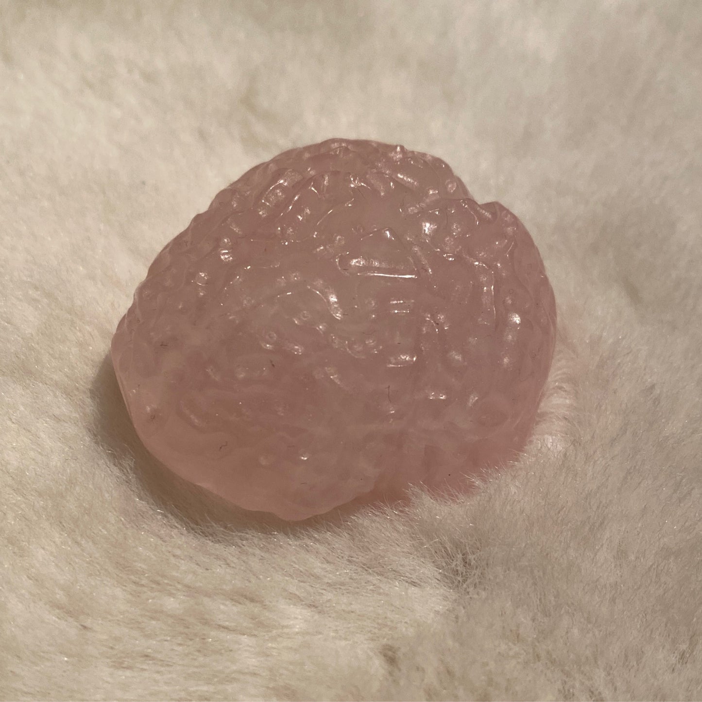 Mini anatomical rose quartz brain sculpture 1-2 inches on soft fabric background