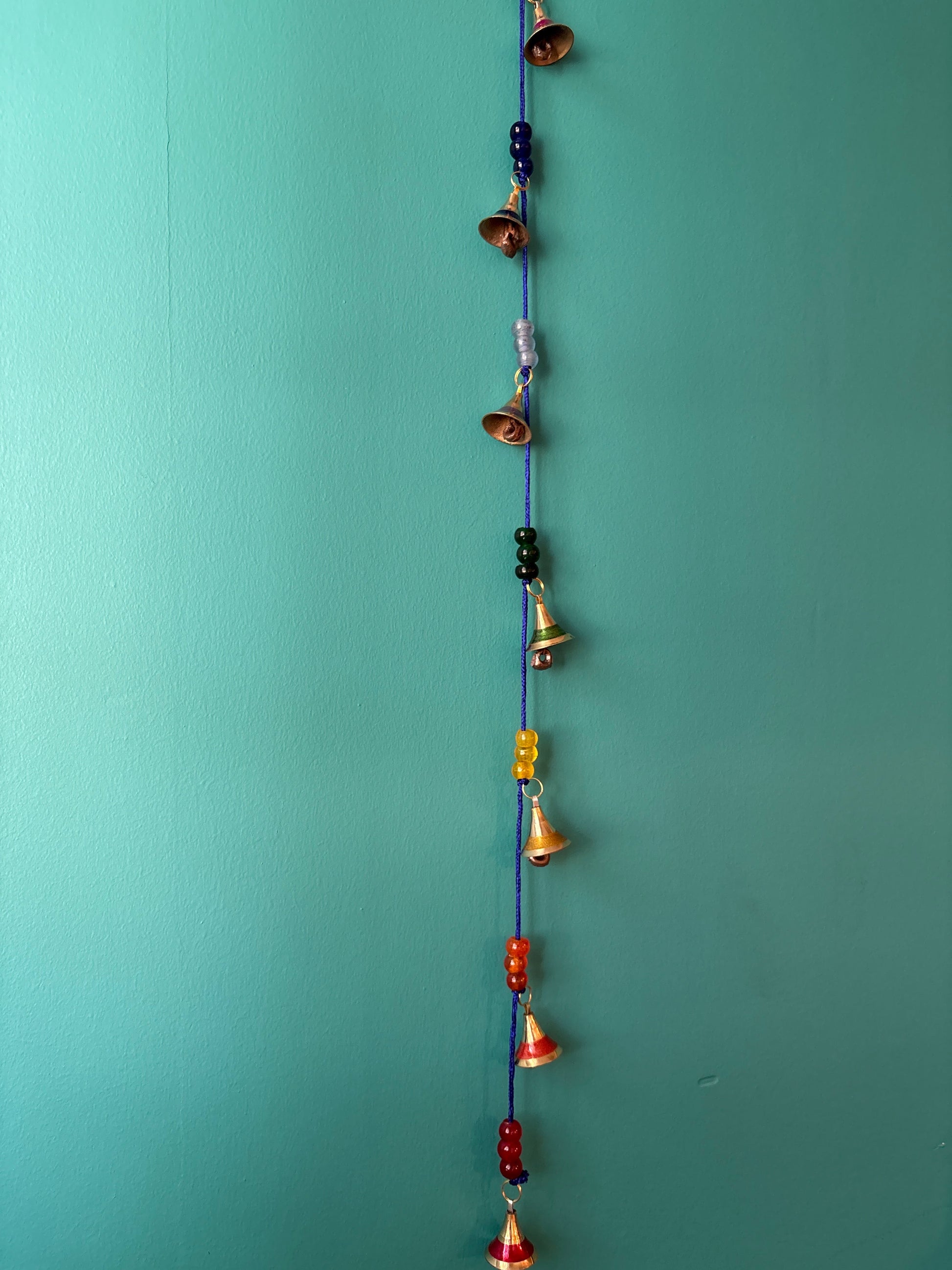 Handcrafted brass chakra bells strung on blue cord with colorful glass beads for meditation and mindfulness practice