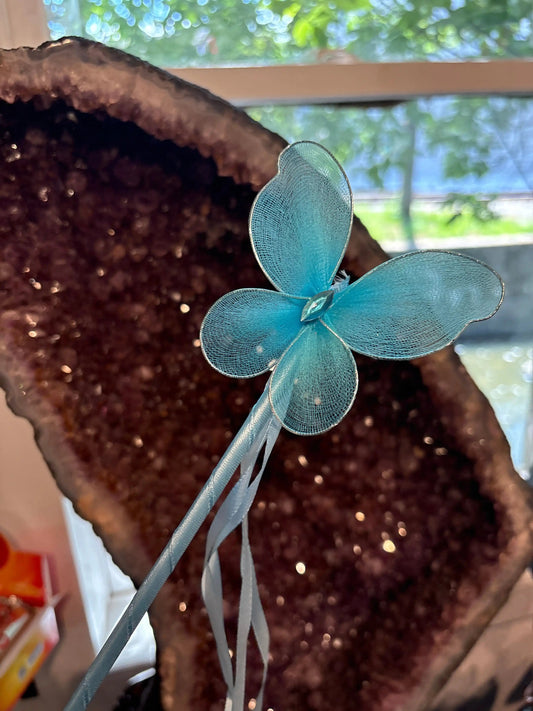 Blue fairy wand with delicate butterfly wings and ribbon streamers against a crystal background