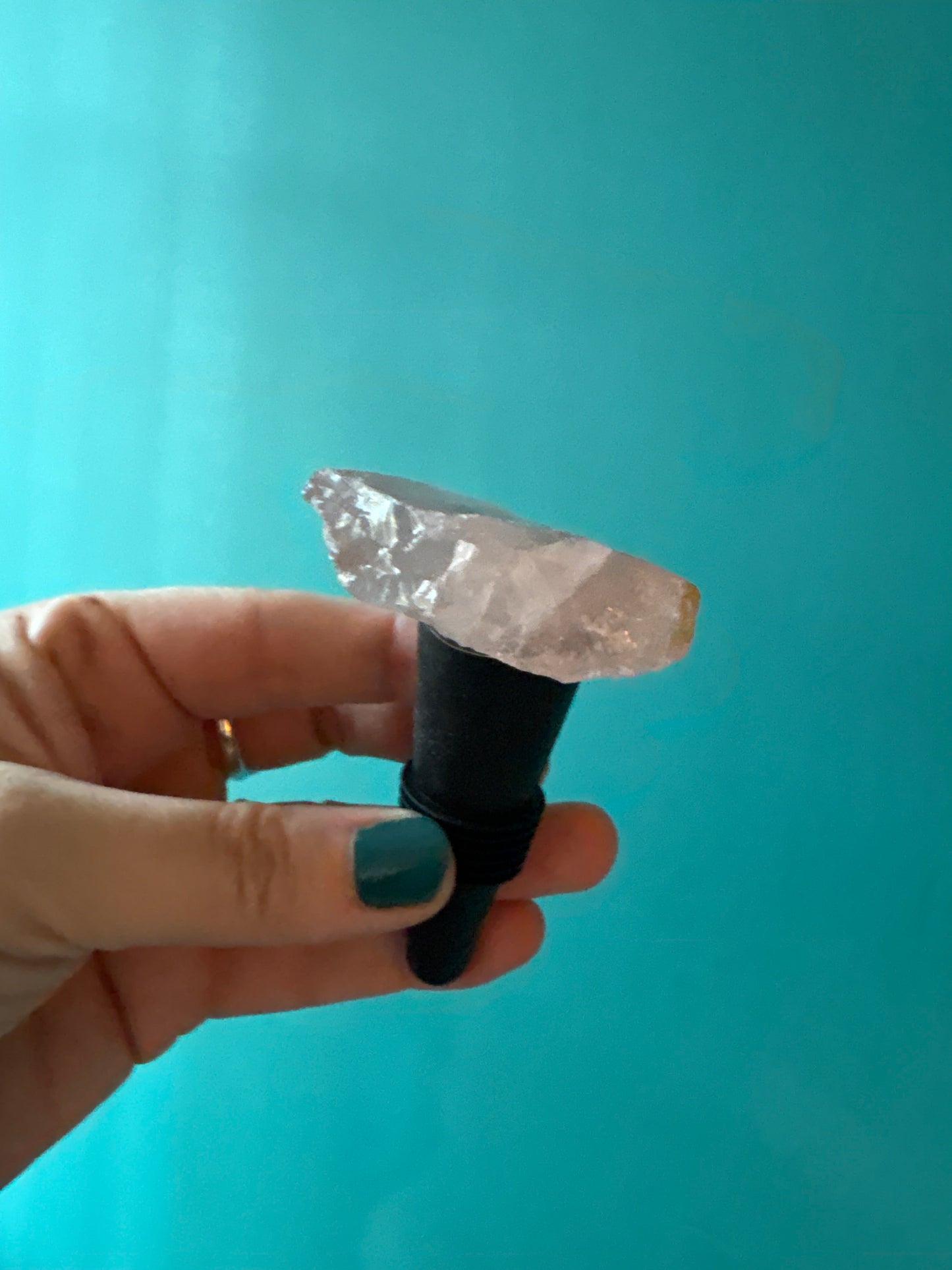 Hand holding a crystal wine stopper against a blue background