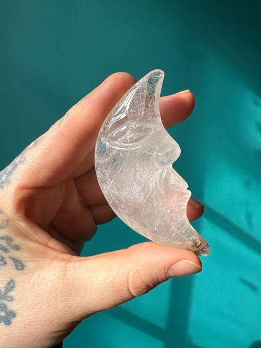 Clear quartz moon carving held in hand, showcasing smooth crystal with moon face details, natural healing crystal quartz moon.