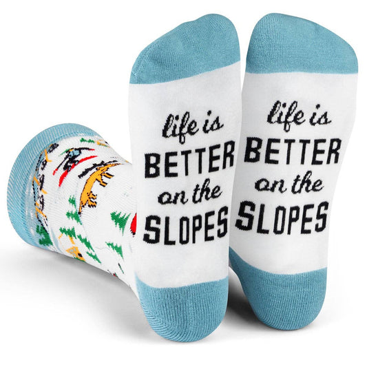 White and blue slopes socks with skiers, snowboarders, and "Life is Better on the Slopes" text on the soles