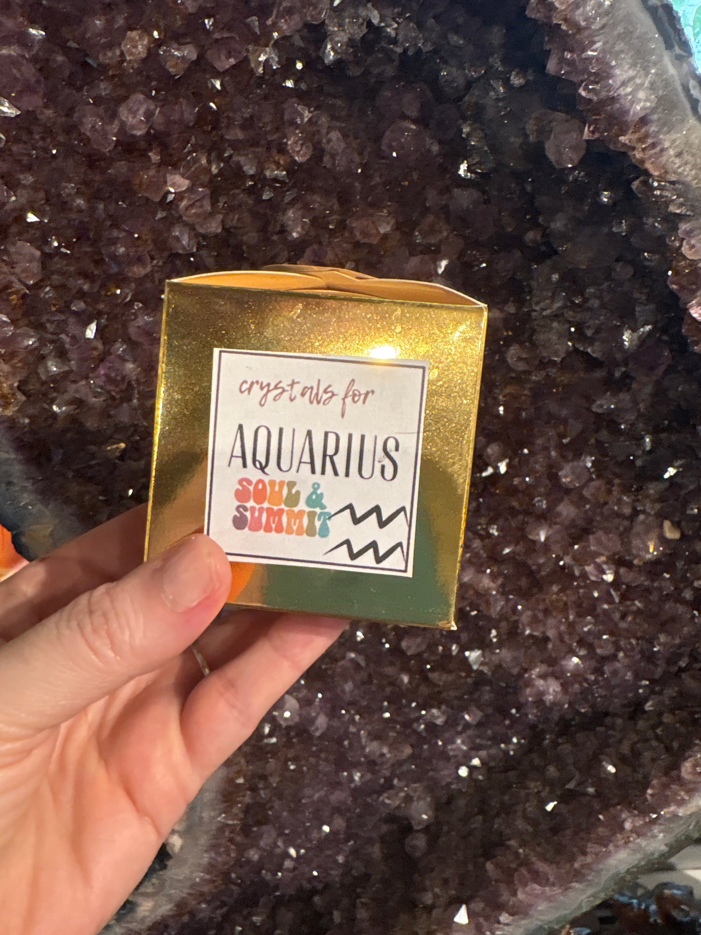 Aquarius Crystal gift box held over amethyst geode background