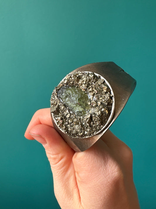 Pyrite Moldavite bracelet held in hand with green and metallic stones on silver band