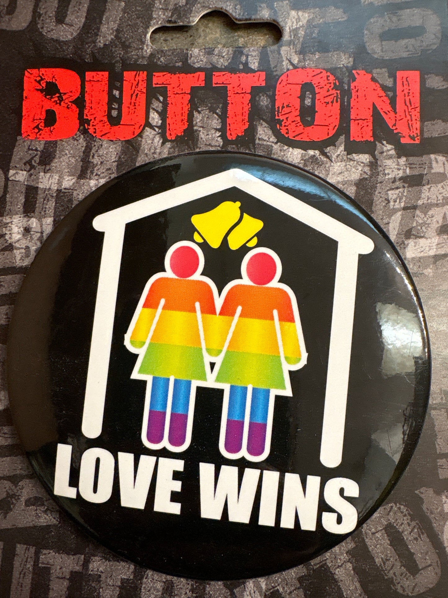 Love wins button with rainbow-colored couple holding hands under a roof and yellow bells above on black background