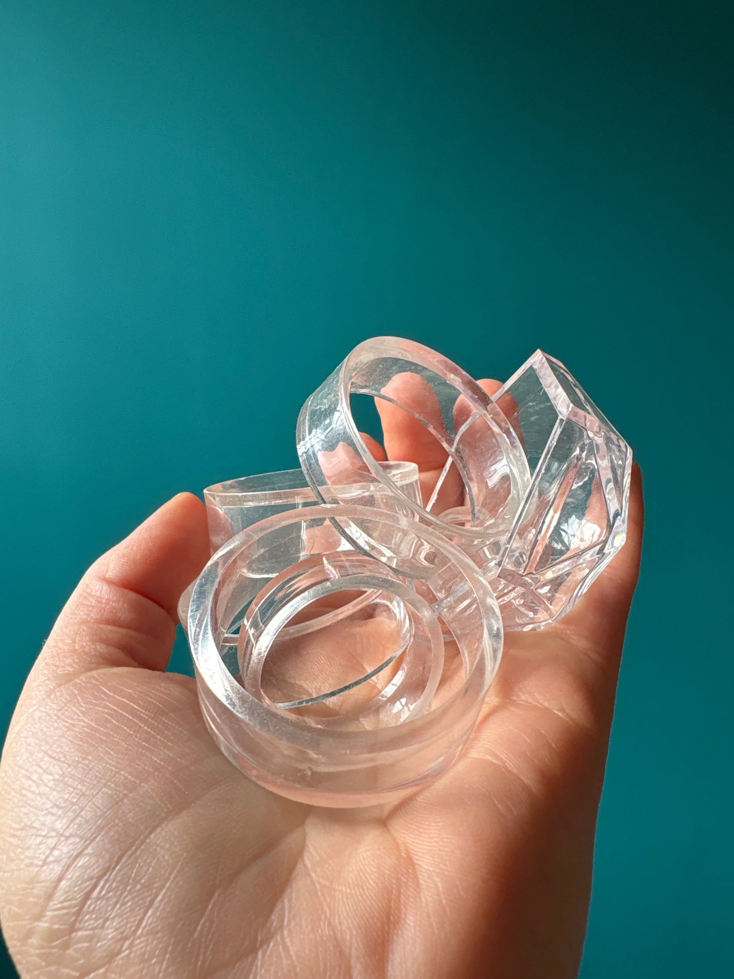 Clear Sphere Stand Acrylic holders displayed on a hand against a teal background