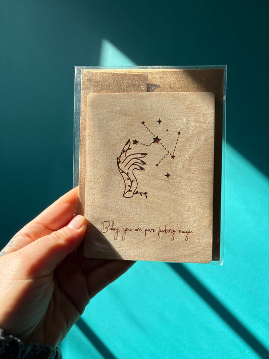 Hand holding pure magic wooden card with constellation and hand illustration against blue background
