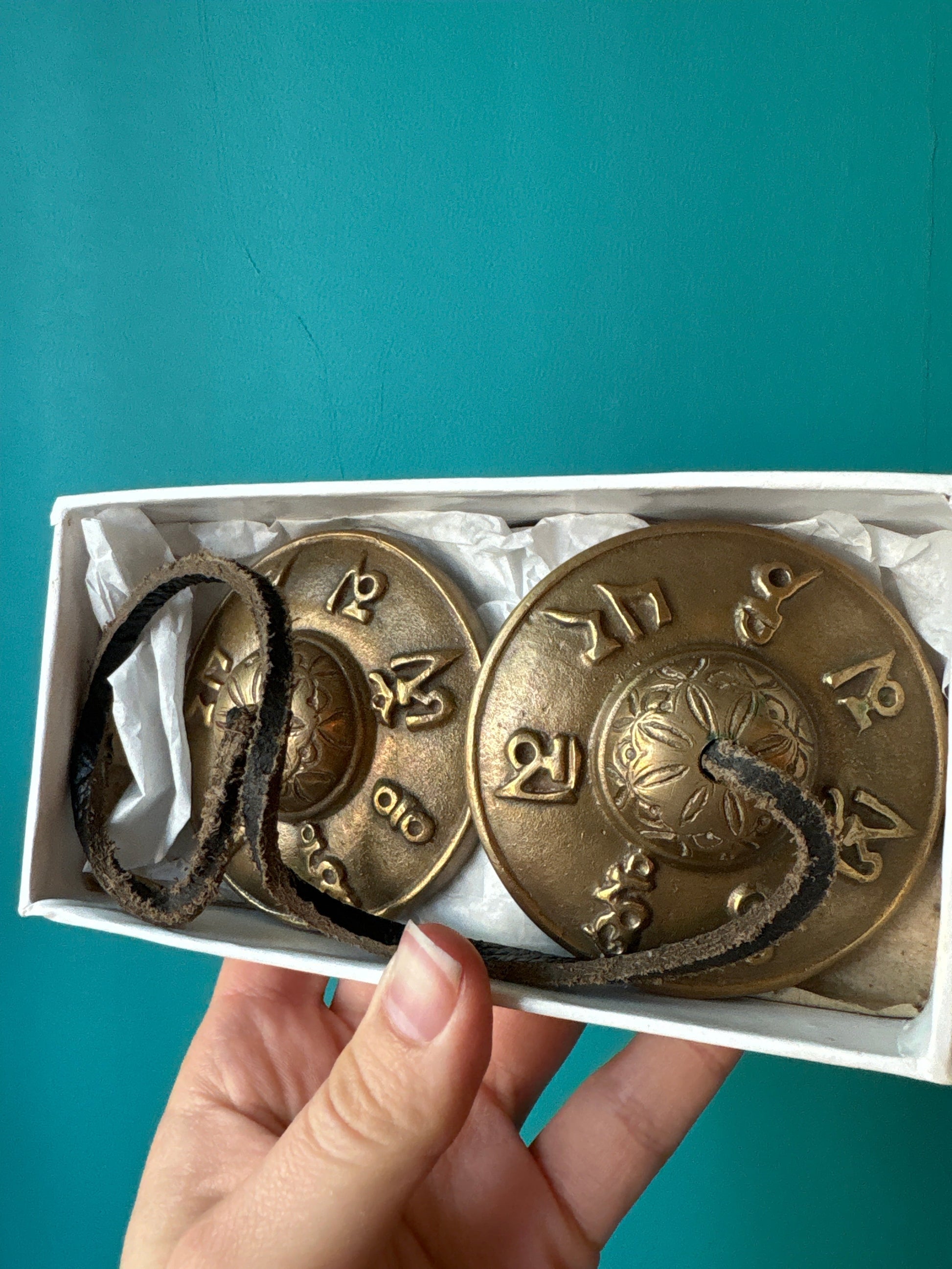 Set of bronze Tingsha Bells with engraved mantra symbols in a white box for meditation and sound therapy