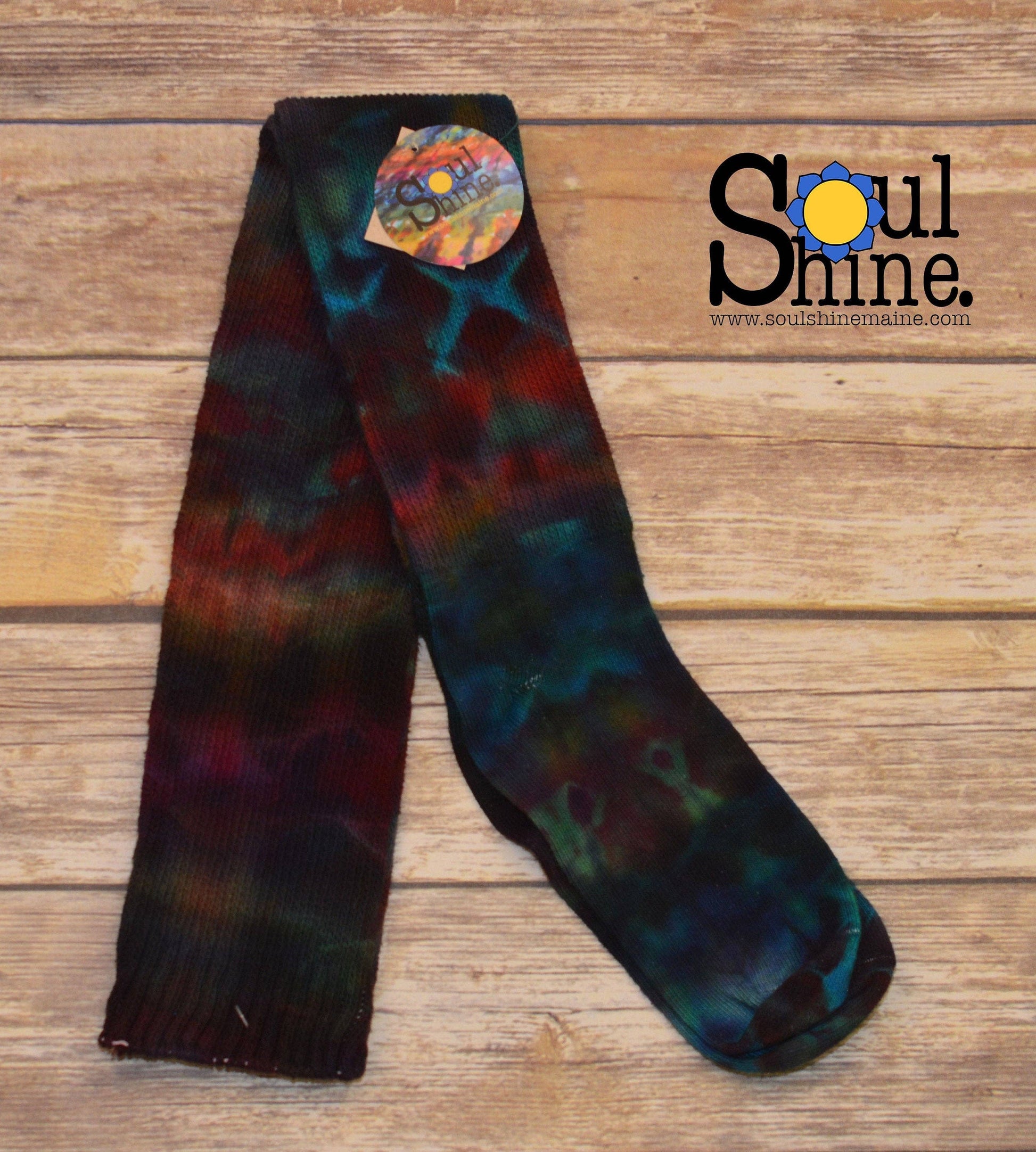 Bold rainbow tie dye thigh high cotton socks laid flat on wooden background