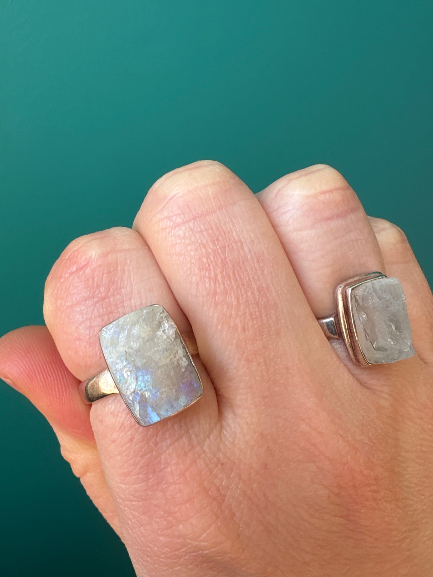 Ring Raw Moonstone with natural healing gemstone on finger against teal background