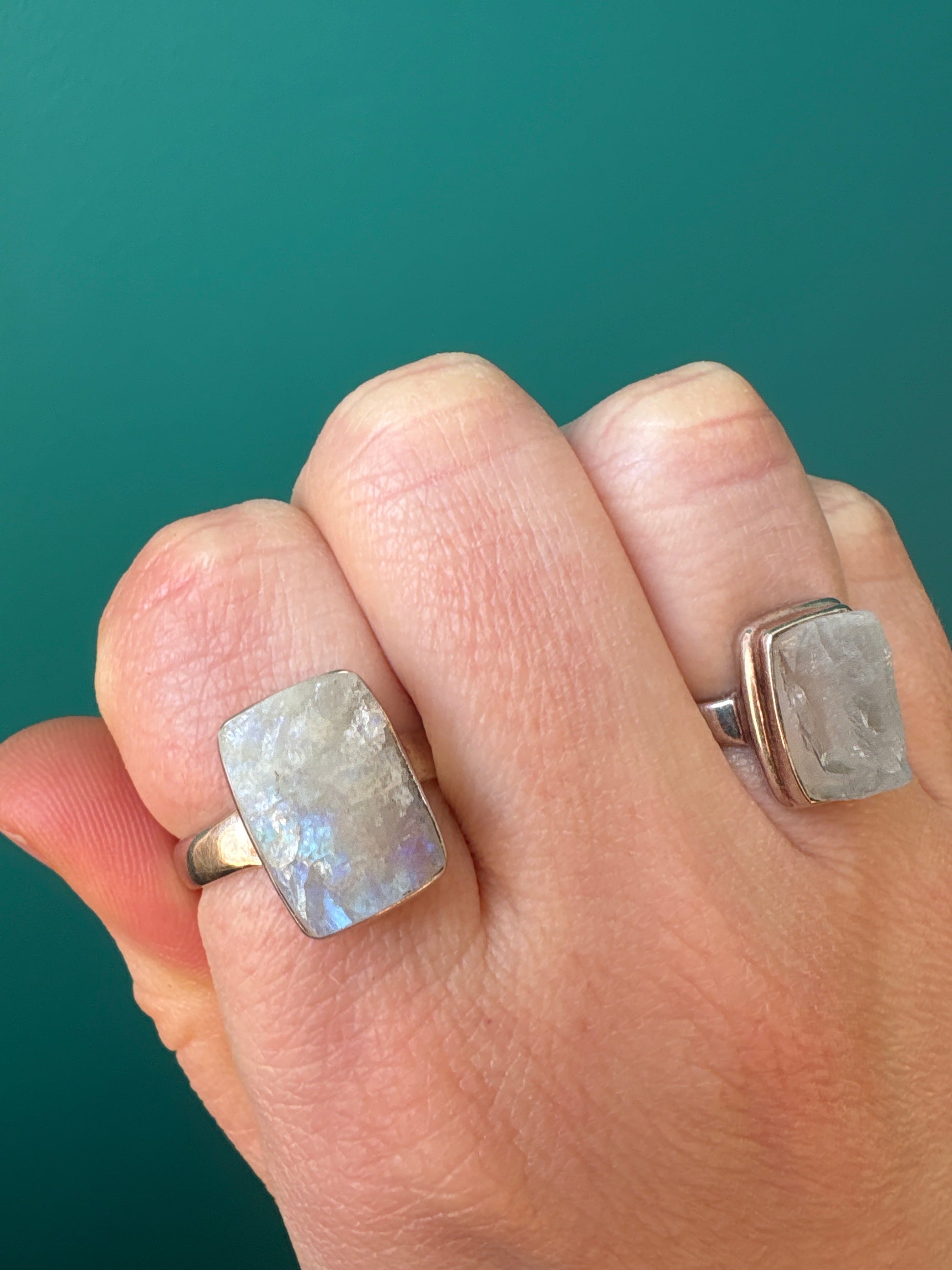 Ring Raw Moonstone with natural healing gemstone on finger against teal background