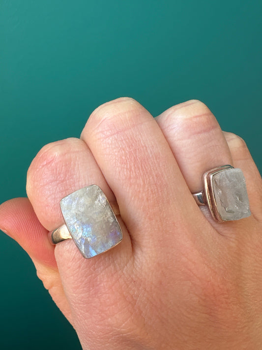 Ring Raw Moonstone with natural healing gemstone on finger against teal background