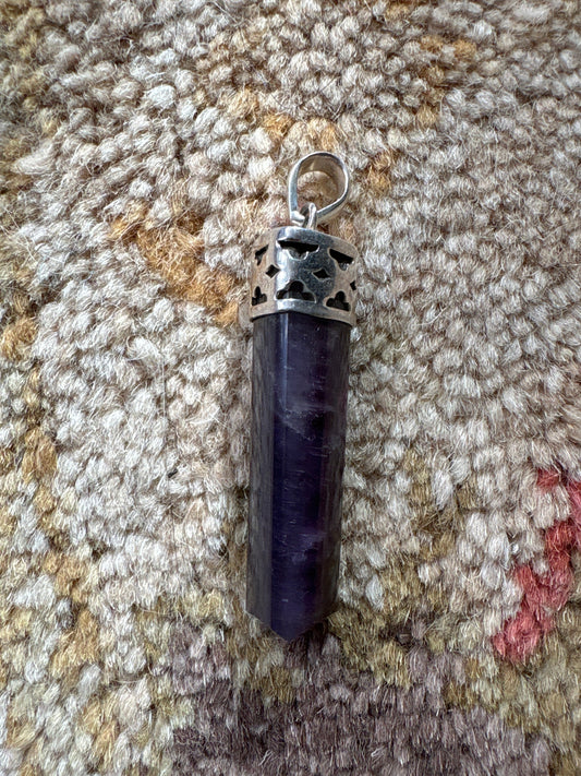 Amethyst polished point pendant with silver cap on textured fabric background