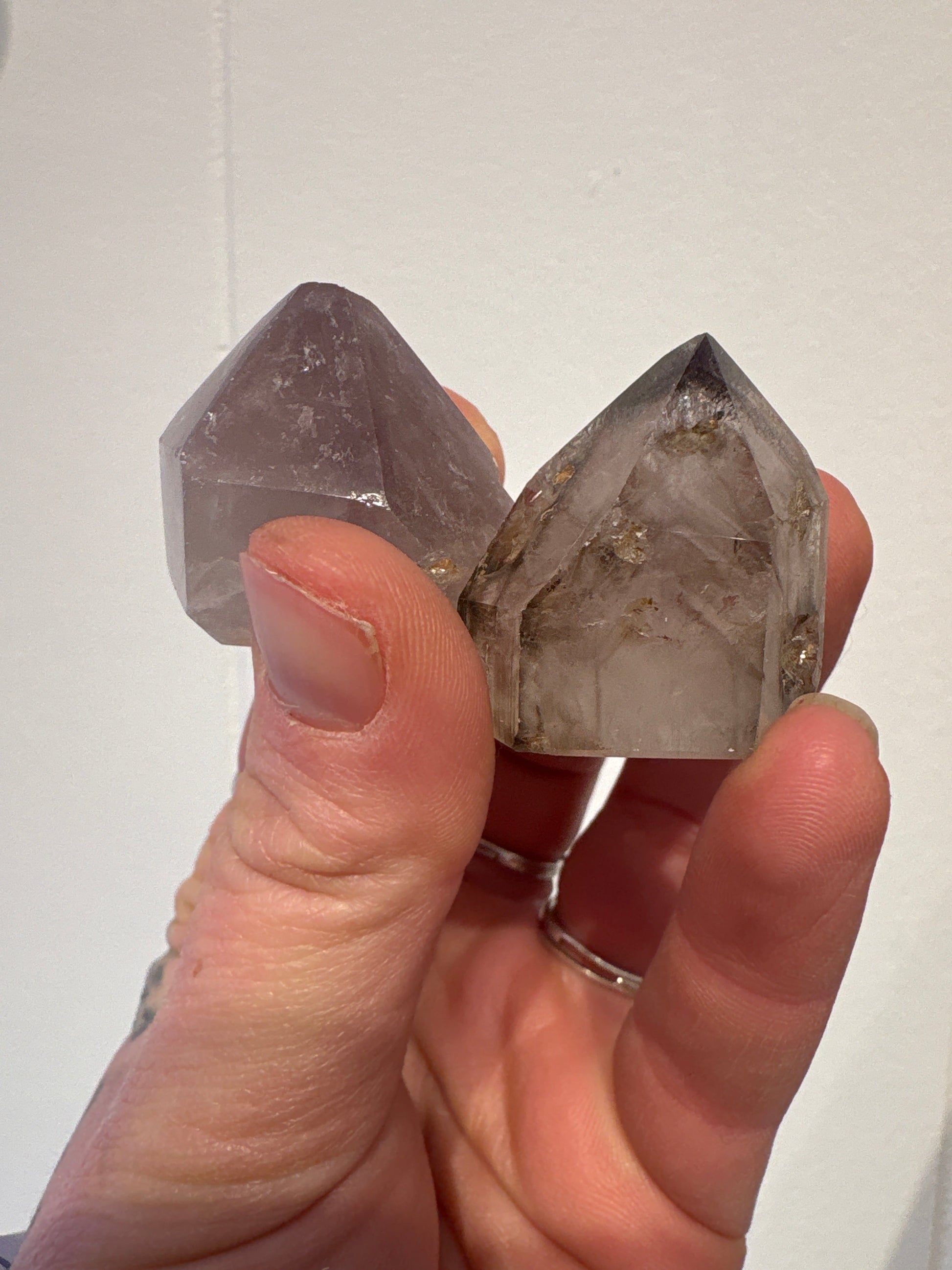 Hand holding two natural Amethyst Points with calming purple hues and clear crystal formations