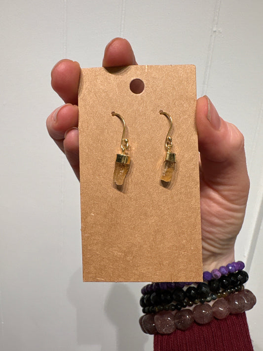 Hand holding card displaying gold topaz earrings with hook design