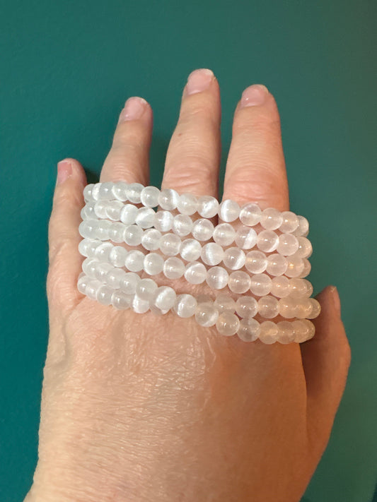 Clear 8mm Selenite bracelet beads shown on hand for energy purification and cleansing.