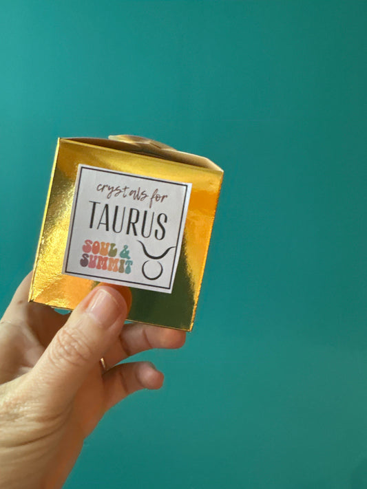 Taurus Crystal Box gold packaging held by hand with turquoise background