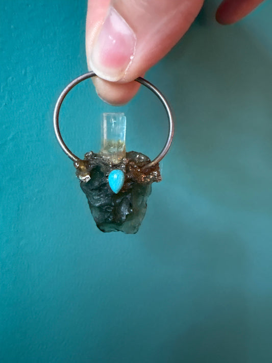Custom made by Syd pendant featuring aquamarine, turquoise, and moldavite gemstones on a metal hoop.
