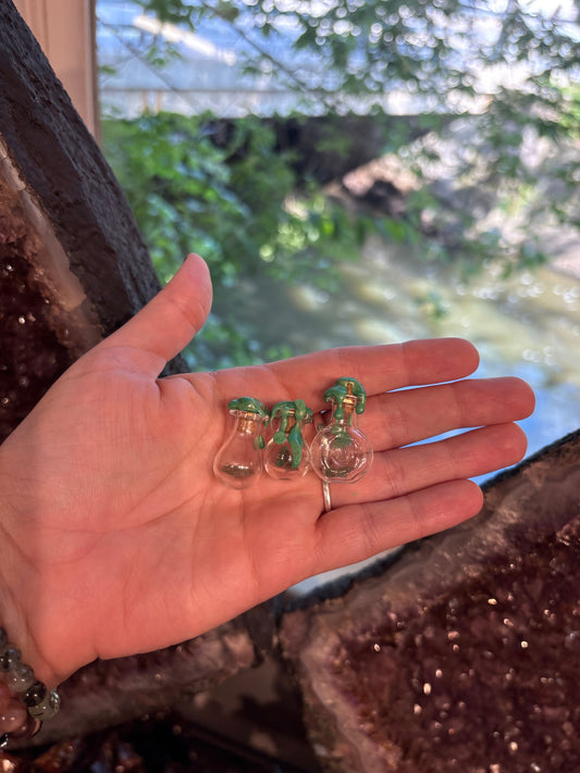Hand holding three small Moldavite Spell Jars with green stone accents for spiritual transformation and growth
