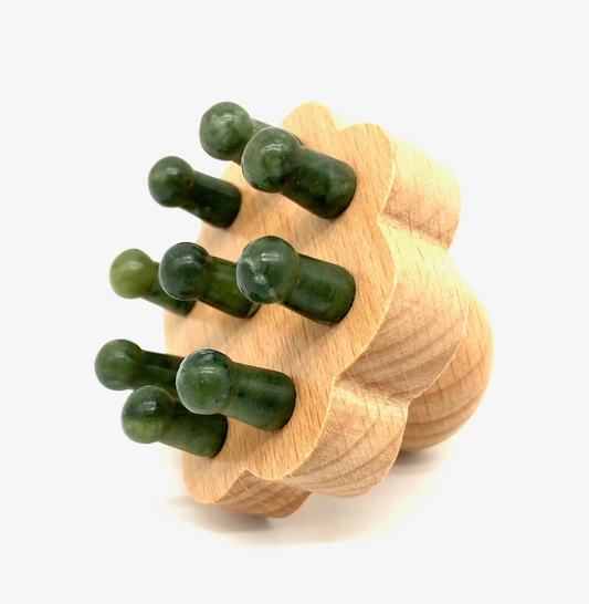 Jade head massager with natural green jade stone tips on wooden base for scalp relaxation and improved circulation