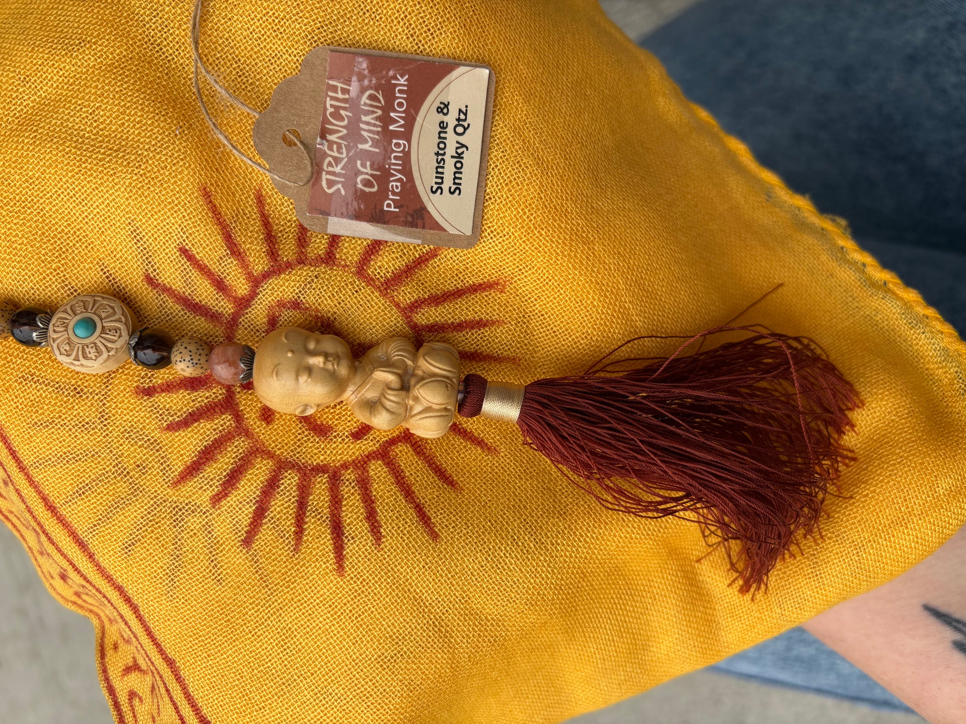 Decorative buddha necklace with beads and tassel on a yellow fabric background