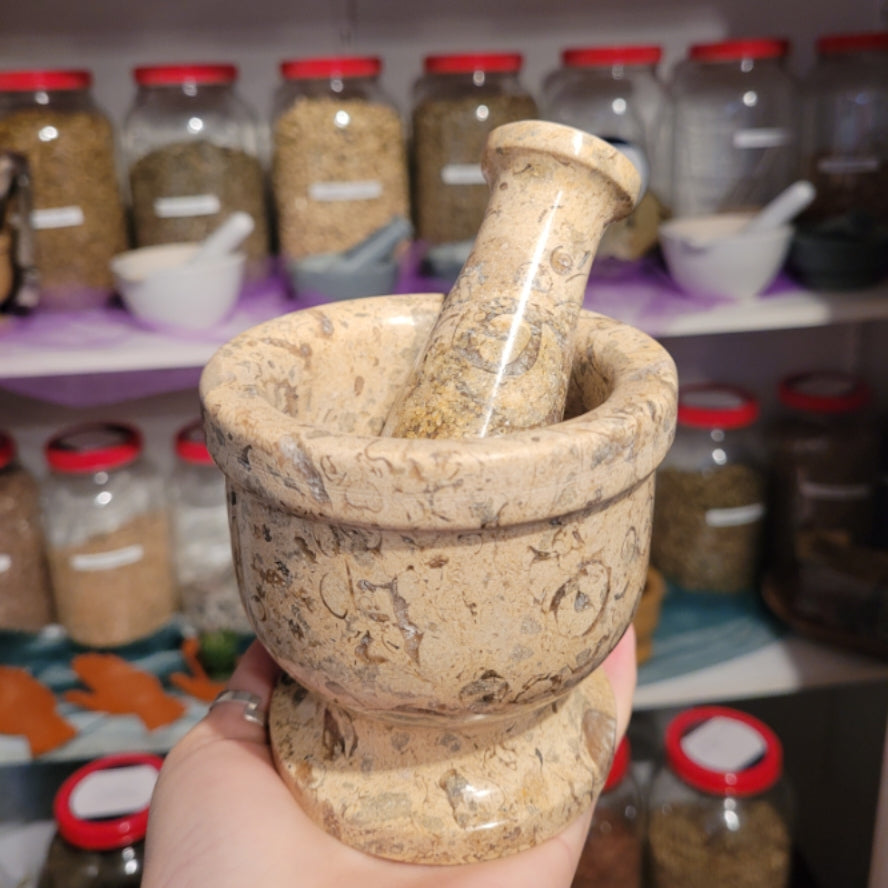 Handheld stone mortar and pestle with natural color variations in a spice shop background