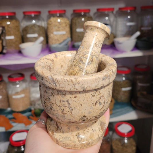 Handheld stone mortar and pestle with natural color variations in a spice shop background