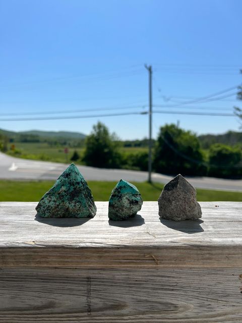 Top polished African turquoise point stones of varying sizes on a wooden surface outdoors