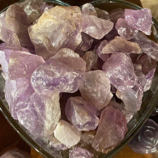 Raw amethyst chunks with natural purple hues in a heart-shaped container