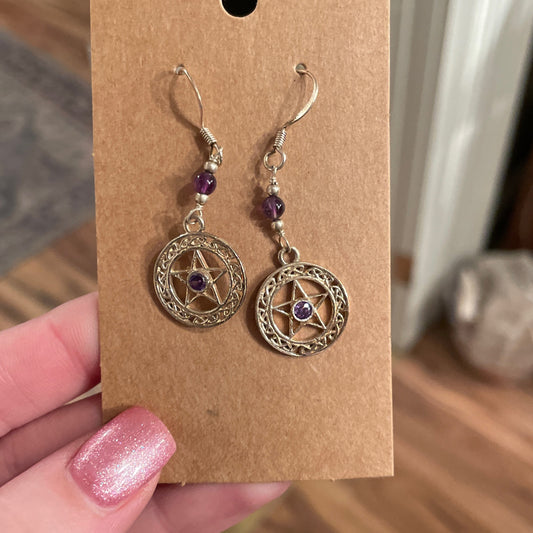 Amethyst pentacle earrings with silver-tone metal and purple gemstone accents on brown card holder
