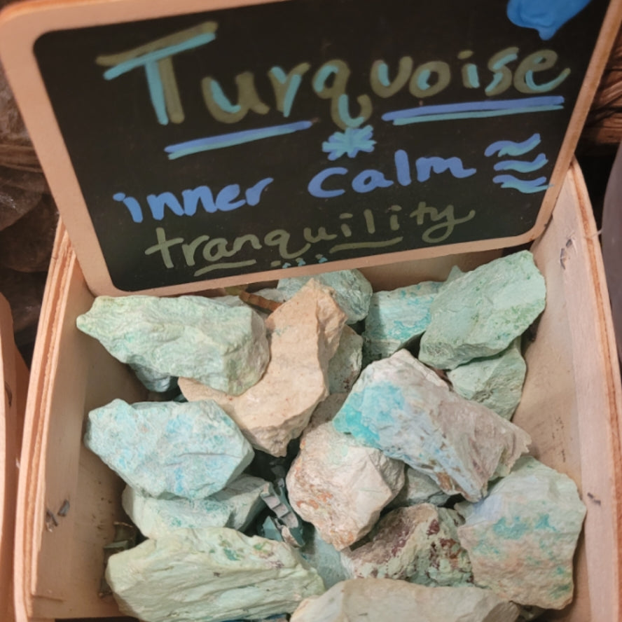 Raw turquoise stones in a wooden box with a sign promoting inner calm and tranquility